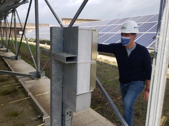 Technician in a hard hat checking equipment at a solar array
